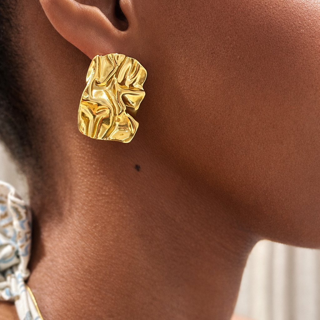 Gold earring worn by a person with a blurred background