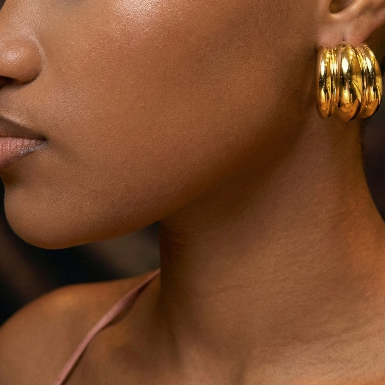 Close-up of a woman wearing gold hoop earrings. 