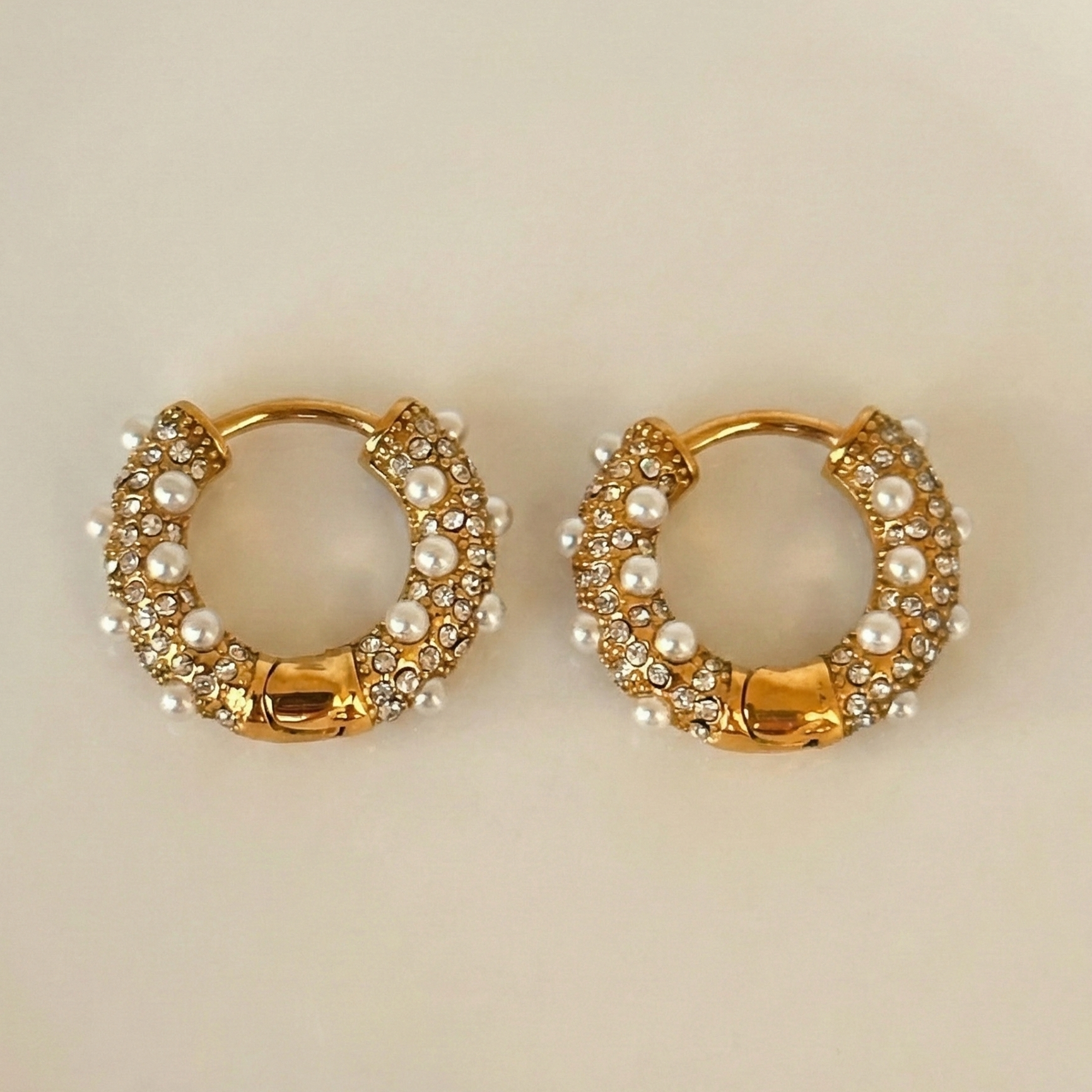Pair of gold hoop earrings with pearl and gemstone accents. 