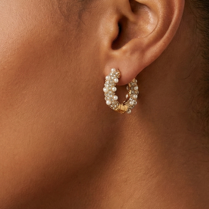 Close-up of an ear wearing a gold and pearl hoop earring.