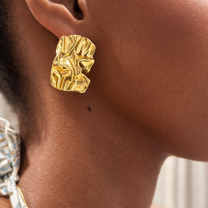Gold earring worn by a person with a blurred background